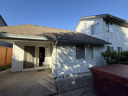 Light-colored two-story house with patio and red hot tub, photographed in July 2025. Painted by Pearl Painters, Portland.
