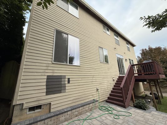 Beige two-story house with vinyl siding in Portland; painter's gray paint test swatches on wall. Pearl Painters project.