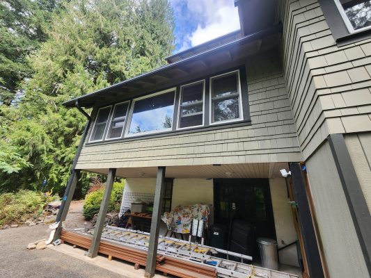 Gentry house in Portland with greenish-gray siding, large windows, and painter ladders; Pearl Painters’ painting area. Move-in Aug 2025.