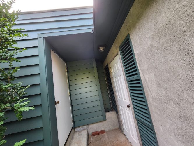 Building corner with green siding, white doors, and green shutters in Portland. Painter: Ralph Barron, August 2025. Pearl Painters.