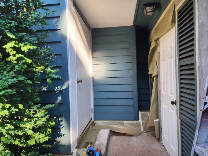 Pearl Painters painted a blue-sided house with white doors in Portland; painting supplies sit outside. Finished Aug 2025.