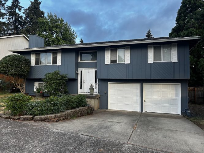 A two-story blue house with white trim and double garage doors was painted by Pearl Painters in Portland.