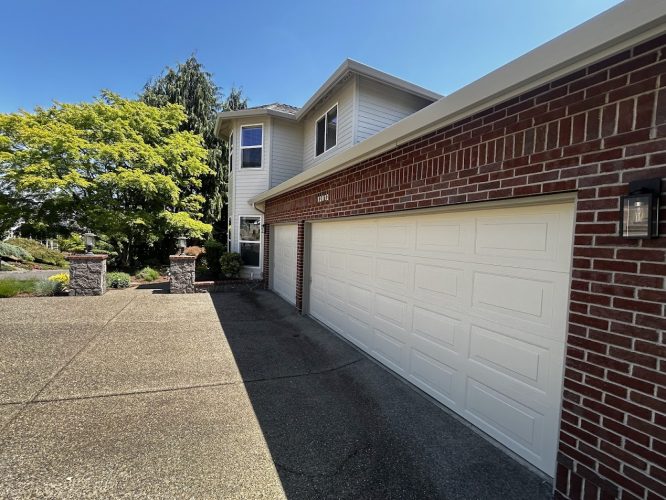 The two-story Mackey-Hinzdel house in Portland features red brick, light siding, a large white garage door, concrete driveway, and landscaped yard. Exterior painting upgrades by Pearl Painters are scheduled for June 2025.