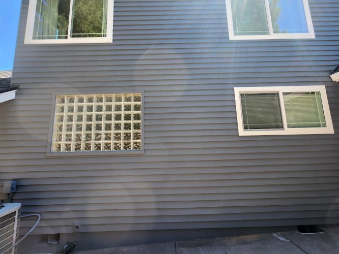Roberts exterior in Portland: gray siding, three windows, concrete, HVAC unit. Photo shows area painted by Pearl Painters July 2025.