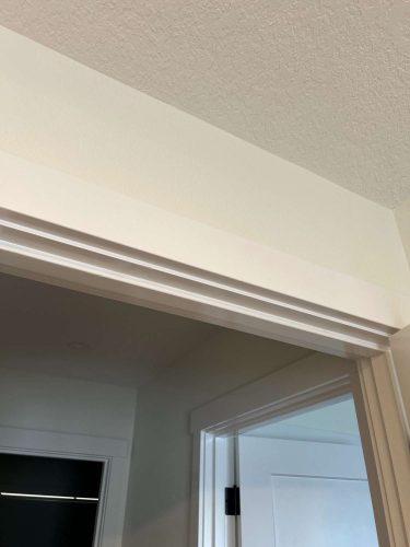 Painter Arnold completed this interior painting in Portland, featuring a white door frame with crown molding, beige walls, and a textured ceiling. Pearl Painters provided the service in May 2025.