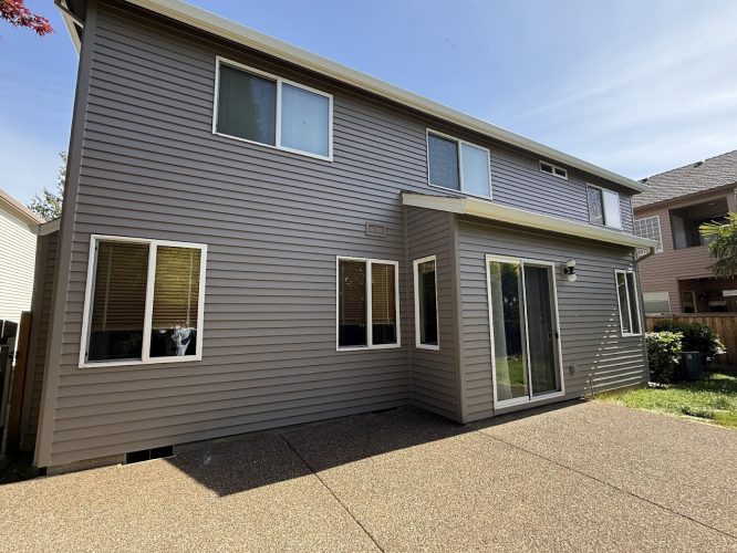 A two-story Hendricks home in Portland with gray siding, multiple windows, and a sliding glass door to a concrete patio. Pearl Painters will complete painting by May 2025.