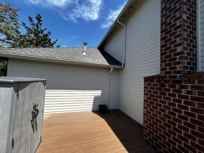 A painting by Mackey-Hinzdel shows a wooden deck with a storage box, brick chimney, and beige siding under a sunny sky. Painted in Portland, suitable for Pearl Painters' June 2025 display.