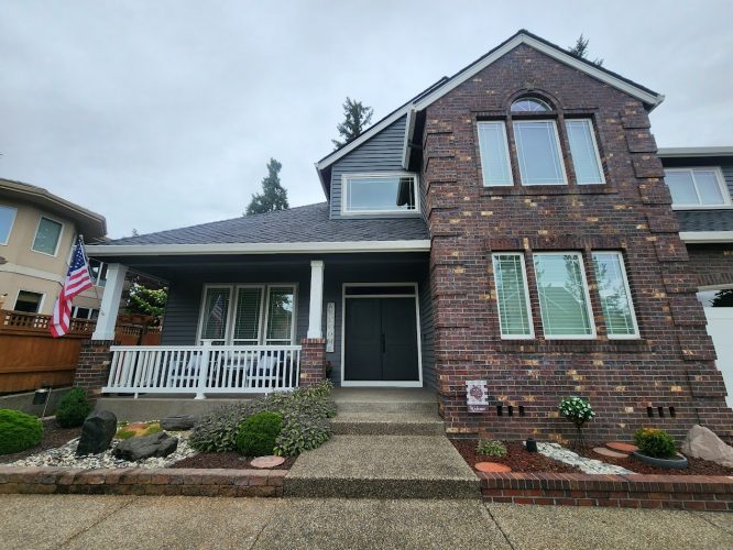 Roberts' two-story brick house in Portland, freshly painted by Pearl Painters, with porch, double doors, and flag.