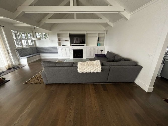 A painter in Portland, inspired by Duffy’s designs, created a timeless living room with a gray sectional sofa, white built-in cabinet and fireplace, wooden floors, and a vaulted white ceiling with exposed beams. Pearl Painters can achieve similar painting results.