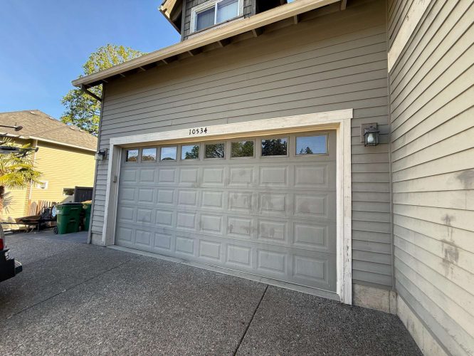 A gray garage door with four upper windows is painted on a beige Austin home at 10534, shown in May 2025. Local painters such as Pearl Painters typically complete similar exterior painting projects.