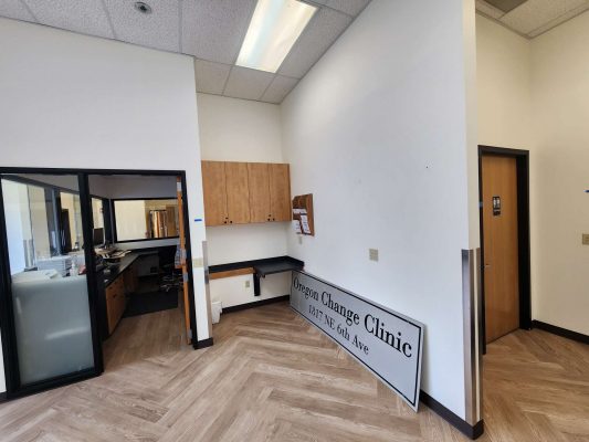 Interior of the Jones office, Portland, May 2025. The photo shows wood cabinets, a counter, bulletin boards, and a large "Oregon Change Clinic" sign. An adjacent office and door are also visible. Pearl Painters completed the painting for this space.