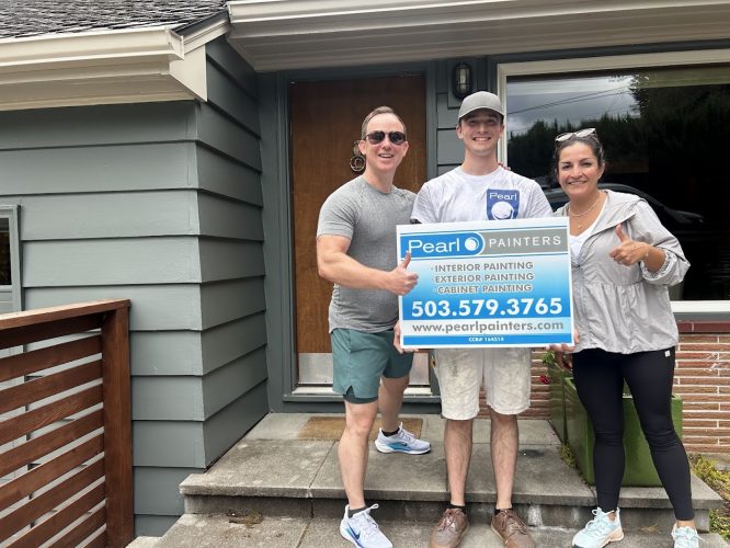 Three people stand outside a Carlton house, holding a Pearl Painters sign for painting services. The sign includes contact details and notes booking into June 2025.