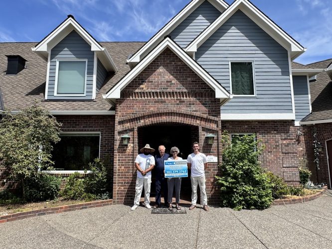 Four people stand in front of a brick house in Portland; two hold a sign with "Anderson ext," phone numbers, and other text. Photo taken June 2025, possibly for Pearl Painters or painting services.