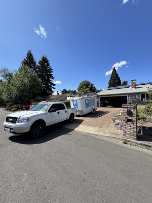 Deppe painter truck and trailer parked in suburban driveway under blue July 2025 sky, possibly for Pearl Painters in Portland.