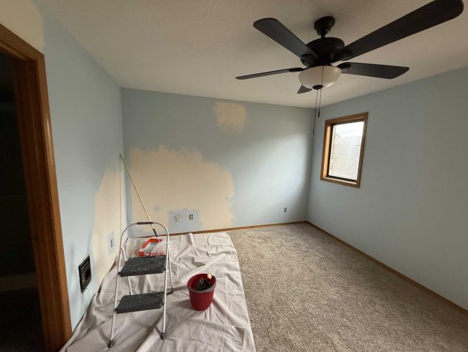 A partially painted interior room in the April 2025 Yates project shows light blue walls, a step ladder, paint supplies, and a drop cloth on the carpet. Pearl Painters, Portland painters, are handling this painting work.
