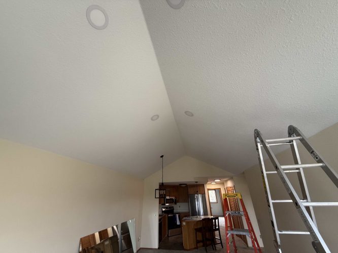 A kitchen and living area in a Yates Interior home, Portland, is shown under renovation with tools and a ladder present. Pearl Painters is the painting contractor. Photo from April 2025.
