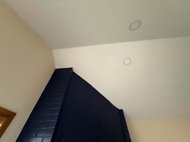 Interior corner from the Yates project by Pearl Painters in Portland, showing a beige wall, navy blue brick, and a textured white ceiling with two recessed lights—painting inspiration for April 2025 renovation.
