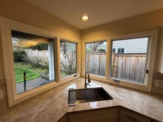 A painter from Pearl Painters in Portland updated this kitchen in April 2025. The painting highlights Mills Interior style, with a marble countertop, modern faucet, and corner windows overlooking a fenced backyard.