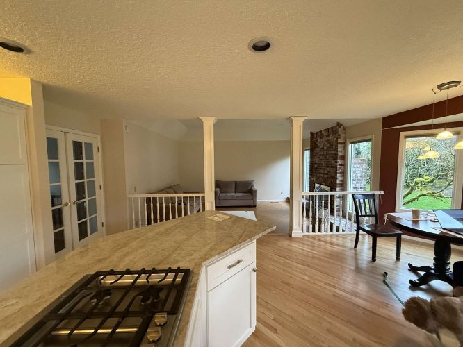 This Mills home in Portland features an open living area with a kitchen island, gas cooktop, hardwood floors, sofa, and large windows facing the backyard. Pearl Painters can help refresh your interior painting for April 2025.