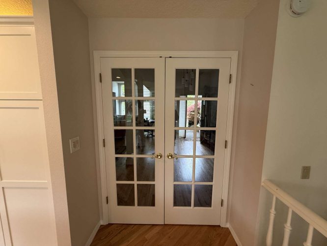 White French doors with glass panes open to a hardwood-floored interior with greenery views at Mills in Portland. Pearl Painters can refresh the painting for an updated look this April 2025.