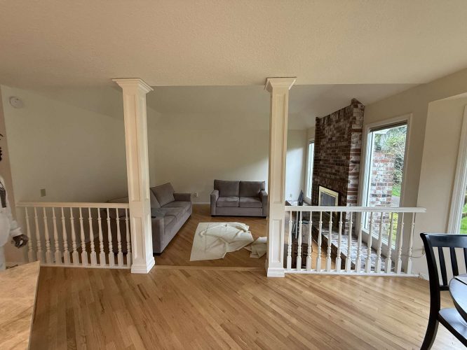 A Portland living room with hardwood floors, two gray sofas, a brick fireplace, and large windows. Pearl Painters completed the painting at Mills for April 2025.