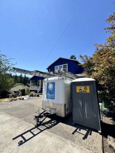A Pearl Painters trailer with ladders and a portable toilet are parked in Jennings' driveway for exterior painting in July 2025.