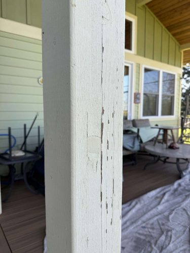 Close-up of a weathered porch post with peeling white paint at a McCaffery home, April 2025. Outdoor furniture and covered floor visible. Example of exterior painting needs for Portland’s Pearl Painters.