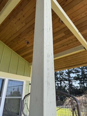 A painter from Pearl Painters in Portland painted this classic McCaffery exterior porch post, shown here with visible cracks under a wood-paneled roof near a window and outdoor seating, April 2025.