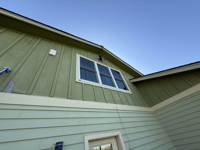 A green exterior McCaffery house in Portland with double upper windows and detailed siding, painted by Pearl Painters, shown under a clear blue April 2025 sky.