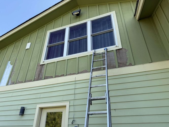 A ladder is positioned against the exterior of a green house near a second-story window in Portland, where patches of paint are missing. The area may need painting or repairs, possibly scheduled with Pearl Painters or another painter in April 2025.