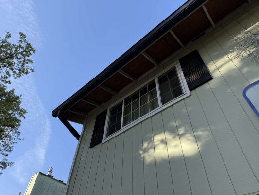 A light green house exterior with black shutters and a large window, painted by Wehage of Pearl Painters in Portland, photographed in April 2025.