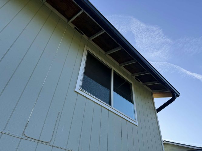 Close-up of a Wehage exterior painting by Pearl Painters in Portland, showing vertical paneling, a double window, and a roof overhang under an April 2025 sky.