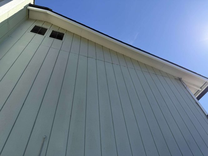 Close-up of a light green Wehage house with vertical siding and two rectangular vents, painted by Pearl Painters in Portland.