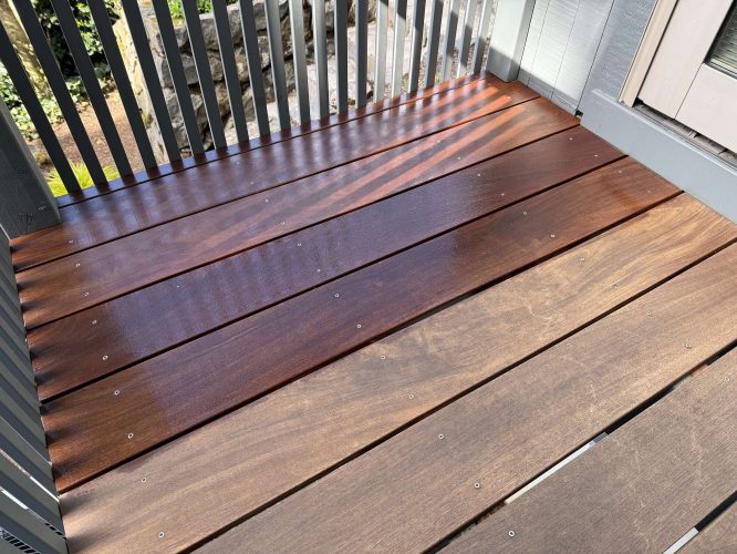 A small exterior deck in Portland features several wooden boards—some newly stained dark brown, others unfinished and lighter. Painting was completed by Pearl Painters in April 2025.