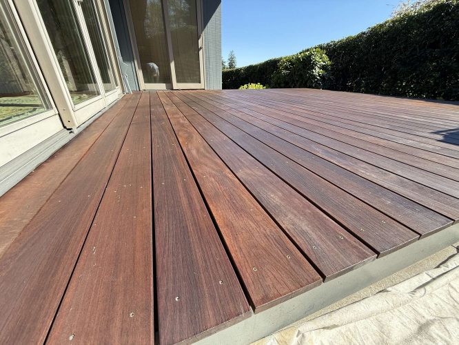 A newly installed exterior wooden deck painted by Pearl Painters in Portland, April 2025. Sunlight highlights the wood grain and screws.