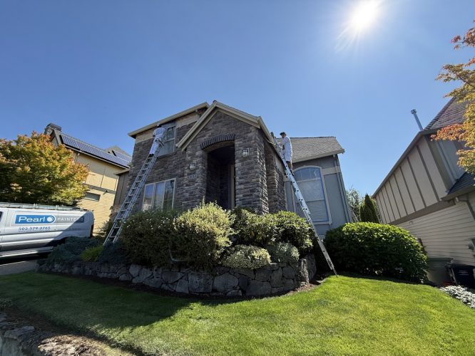 In July 2025, two Pearl Painters paint a stone-front house on ladders in Portland; their van is parked outside.