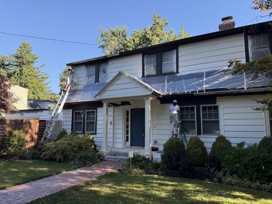 In August 2025, Pearl Painters paint a two-story white house in Portland; Johnson oversees as painters prep and cover windows.