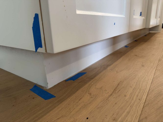 Evans cabinets are featured in this bright kitchen, with blue painter’s tape along the baseboards. The light wood floor highlights the space. Pearl Painters is a painting company based in Portland.