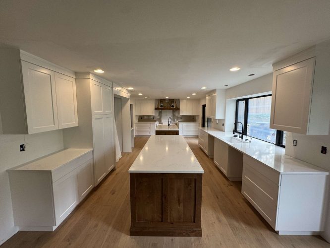 Modern Evans kitchen in Portland painted by Pearl Painters, featuring white cabinets, wood flooring, a wood-base island, quartz countertops, and stainless steel appliances.