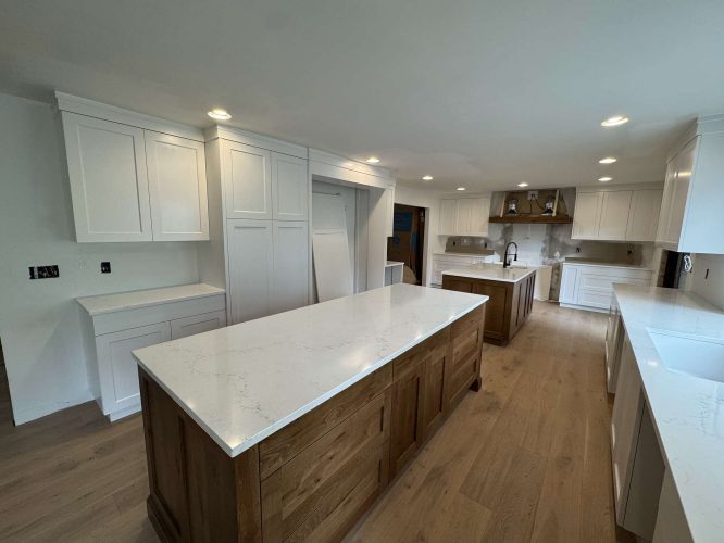 Modern kitchen in Portland with white cabinets, wood islands, marble countertops, recessed lighting, and light wood flooring. Some Evans cabinets and fixtures are unfinished or missing as of April 2025. Painter: Pearl Painters.