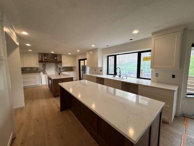 Modern kitchen in Portland with Evans cabinets, marble countertops, two islands, wood flooring, large windows, and recessed lighting. Painted by Pearl Painters.