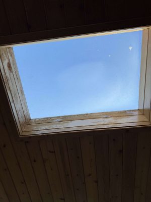 A painter from Pearl Painters captured a square skylight in a wooden ceiling with Hamilton’s clear blue sky visible, suggesting fresh April 2025 air outside.