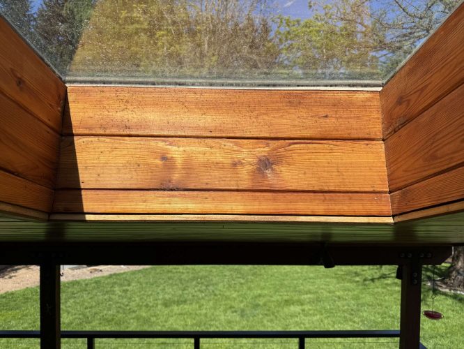 Wood-paneled skylight with clear glass in Hamilton lets sunlight in and provides a view of grass and trees. Ideal for enjoying outdoor scenery. Perfect area for painting or inspiration for a painter; contact Pearl Painters, not just in Portland but available to discuss your project.