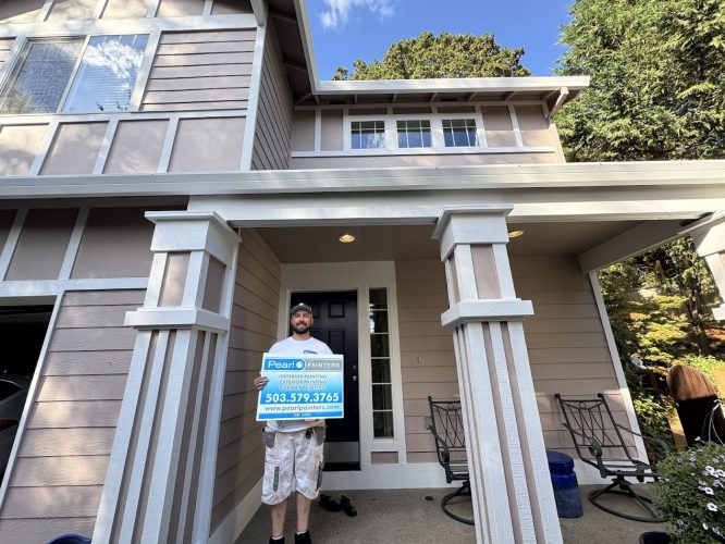 Man on beige house porch in Portland holds Pearl Painters sign about exterior painting, Anderson, and August 2025 projects.