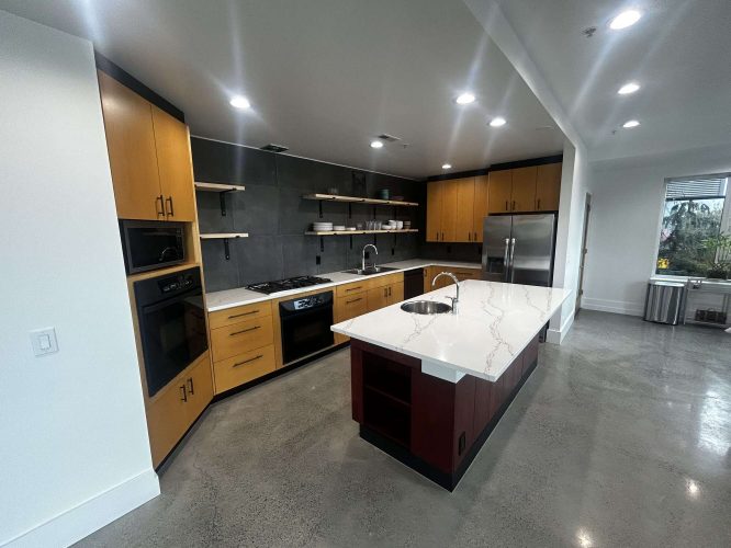 Modern kitchen painted by Pearl Painters in Portland, featuring Isadore light wood cabinets, black appliances, open shelving, marble island with sink, and polished concrete floors—suitable for an April 2025 renovation.