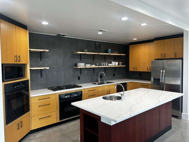 Modern kitchen in Portland featuring Isadore wood cabinets, gray tile backsplash, stainless steel appliances, open shelves, and a white marble island with sink. Painted by Pearl Painters in April 2025.