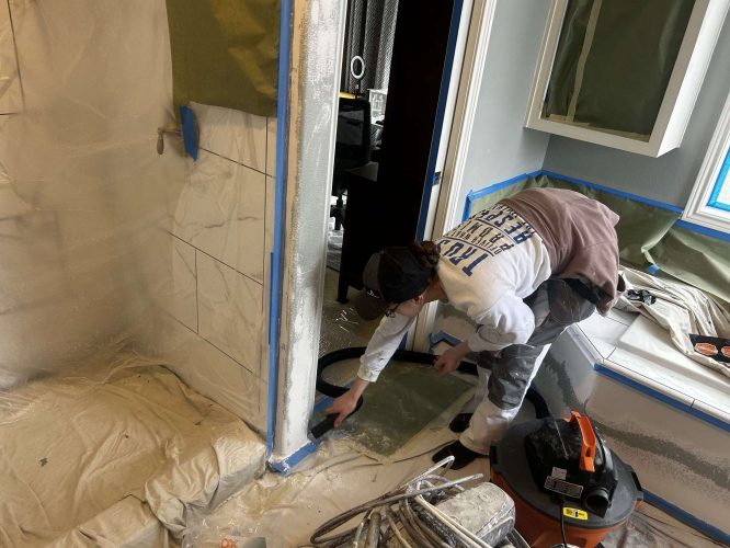 In April 2025, a painter from Pearl Painters in Portland used a vacuum to clean paint dust along a tiled shower edge during an interior bathroom painting job. Surfaces and fixtures in the Mallen Street home were covered with protective sheets and tape.