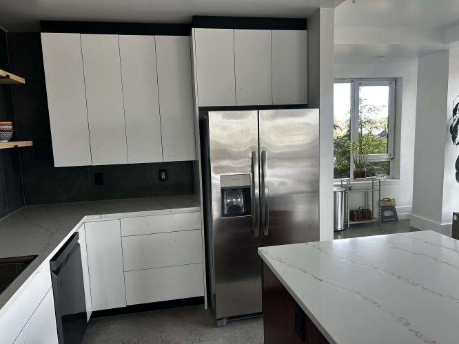 Modern kitchen in Portland with white cabinets, stainless steel refrigerator, and white island countertop; window with plants. Painted by Pearl Painters.