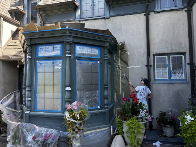 Painter Ralph Barron from Pearl Painters painting an exterior wall near a bay window in Portland, August 2025; plants visible.