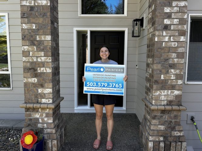 Person in front of Featherstone house holds Pearl Painters sign for Portland painting services, available through Aug 2025.